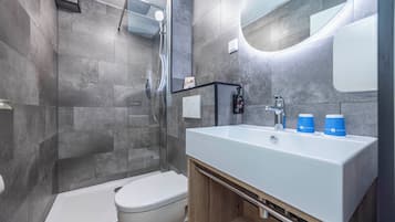A modern bathroom with a shower, toilet, and sink.