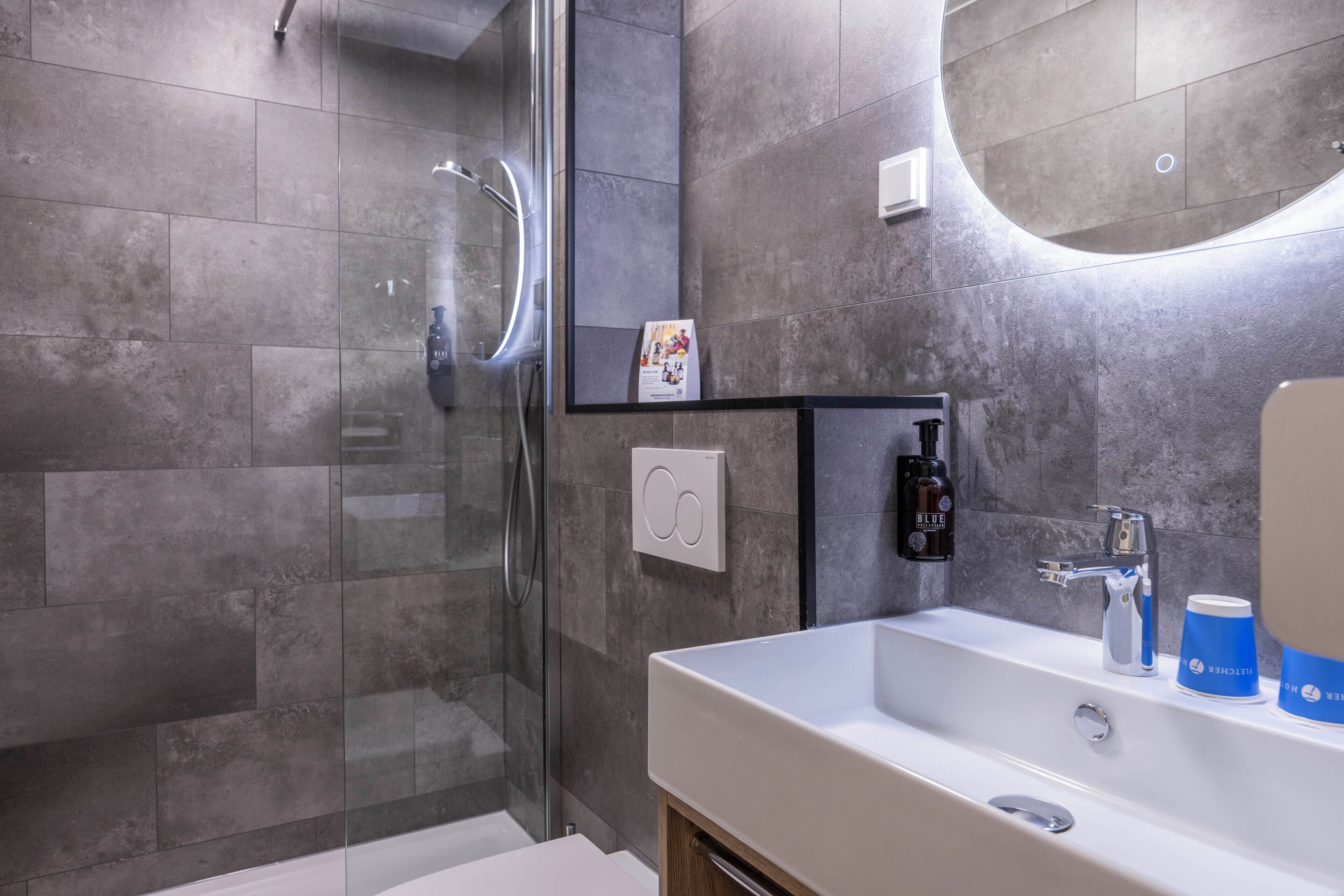 A modern bathroom with a glass shower enclosure, a white sink, and a mirror.
