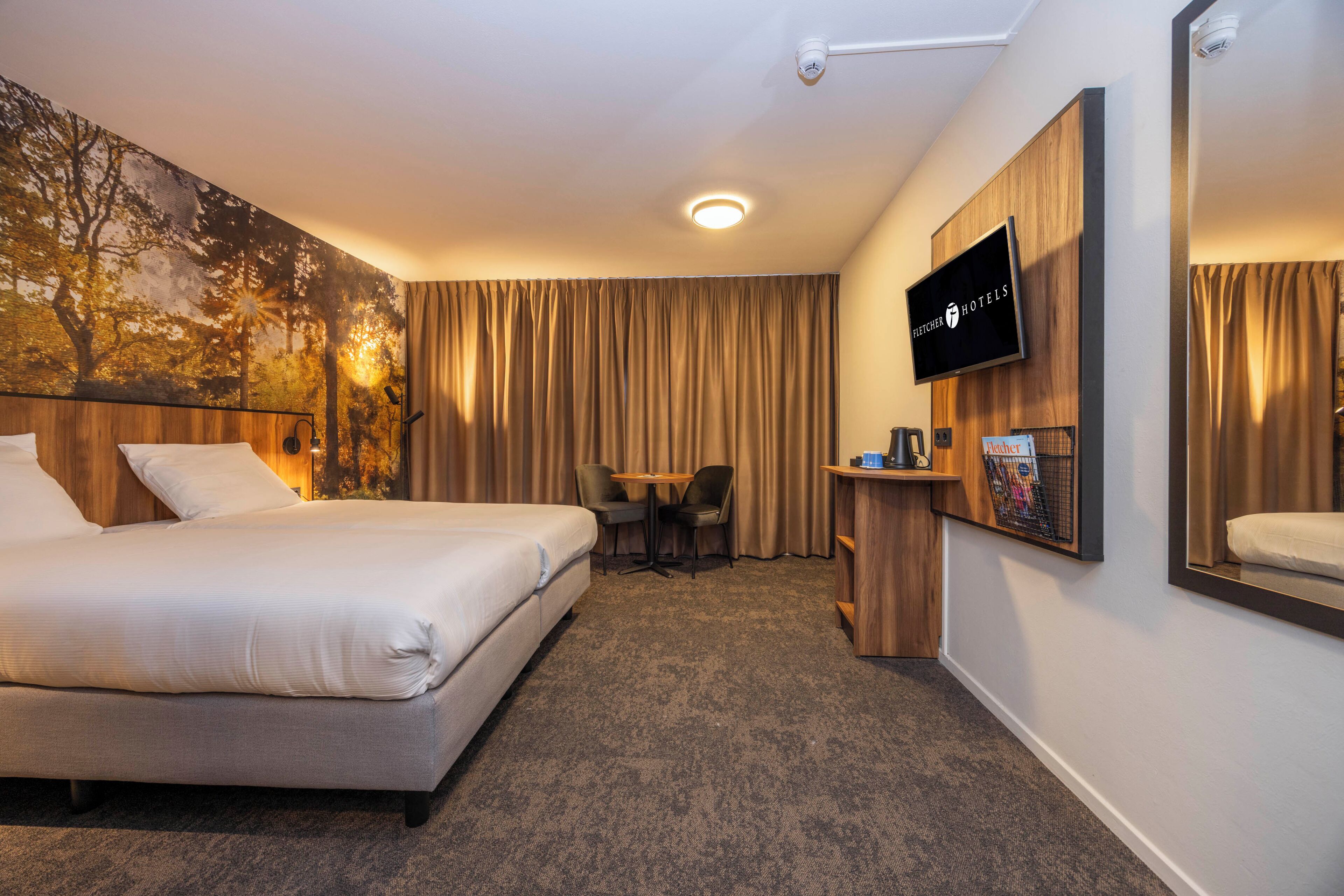 A hotel room with a bed, a desk, a chair, a television, and a large window with curtains.