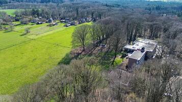 An aerial view of a rural property with a large green field, several buildings, and a prominent brick structure.