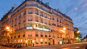 Un hôtel à plusieurs étages, de style architectural européen classique, doté de balcons et d’une façade bien éclairée.