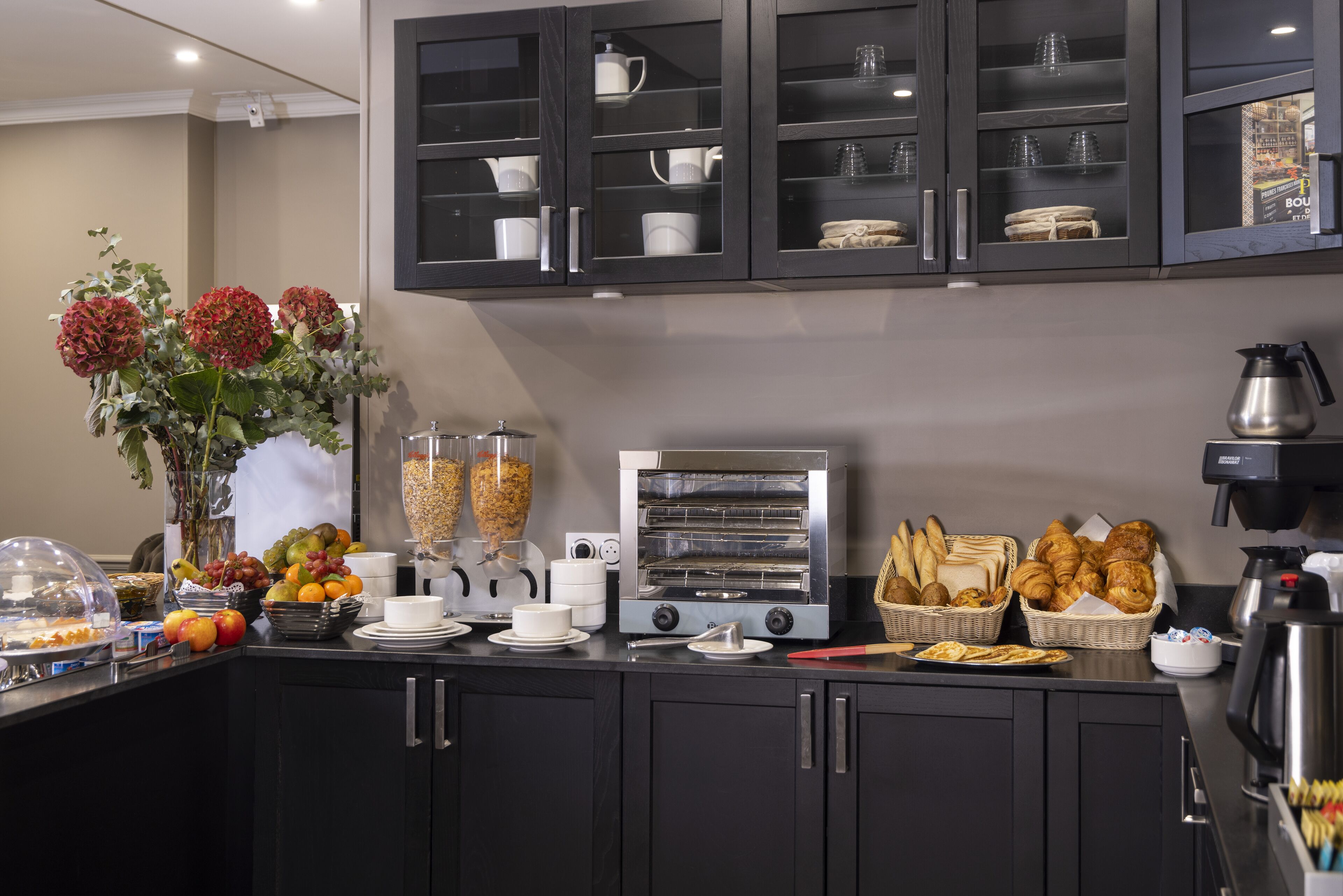 A breakfast buffet setup with a coffee machine, toaster, and various food items.
