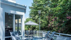 An outdoor patio with metal chairs and a table, surrounded by a white railing and a lamp post.