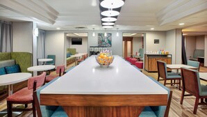 A modern hotel lobby with a long reception desk, comfortable seating, and a central decorative bowl. - Hampton Inn Daytona/Ormond Beach (Ormond Beach)