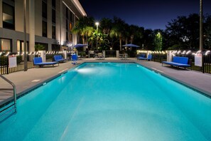 A swimming pool with lounge chairs and umbrellas, surrounded by a fence and palm trees. - Hampton Inn Daytona/Ormond Beach (Ormond Beach)