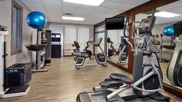 Ein Fitnessstudio mit unterschiedlichen Trainingsgeräten, darunter Laufbänder, Crosstrainer und ein Ergometer.