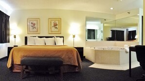 Ett hotellrum med en säng, en stor spegel, ett badkar och två väggmonterade lampor.