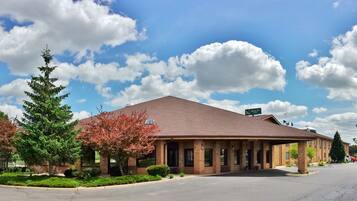 A building with a brick facade, a sign reading "Quality Inn," and a parking lot with a few cars.