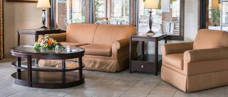 A seating area with a round table, two armchairs, and a small side table with lamps.