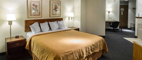 A hotel room with a large bed, two bedside lamps, a desk, and a chair.