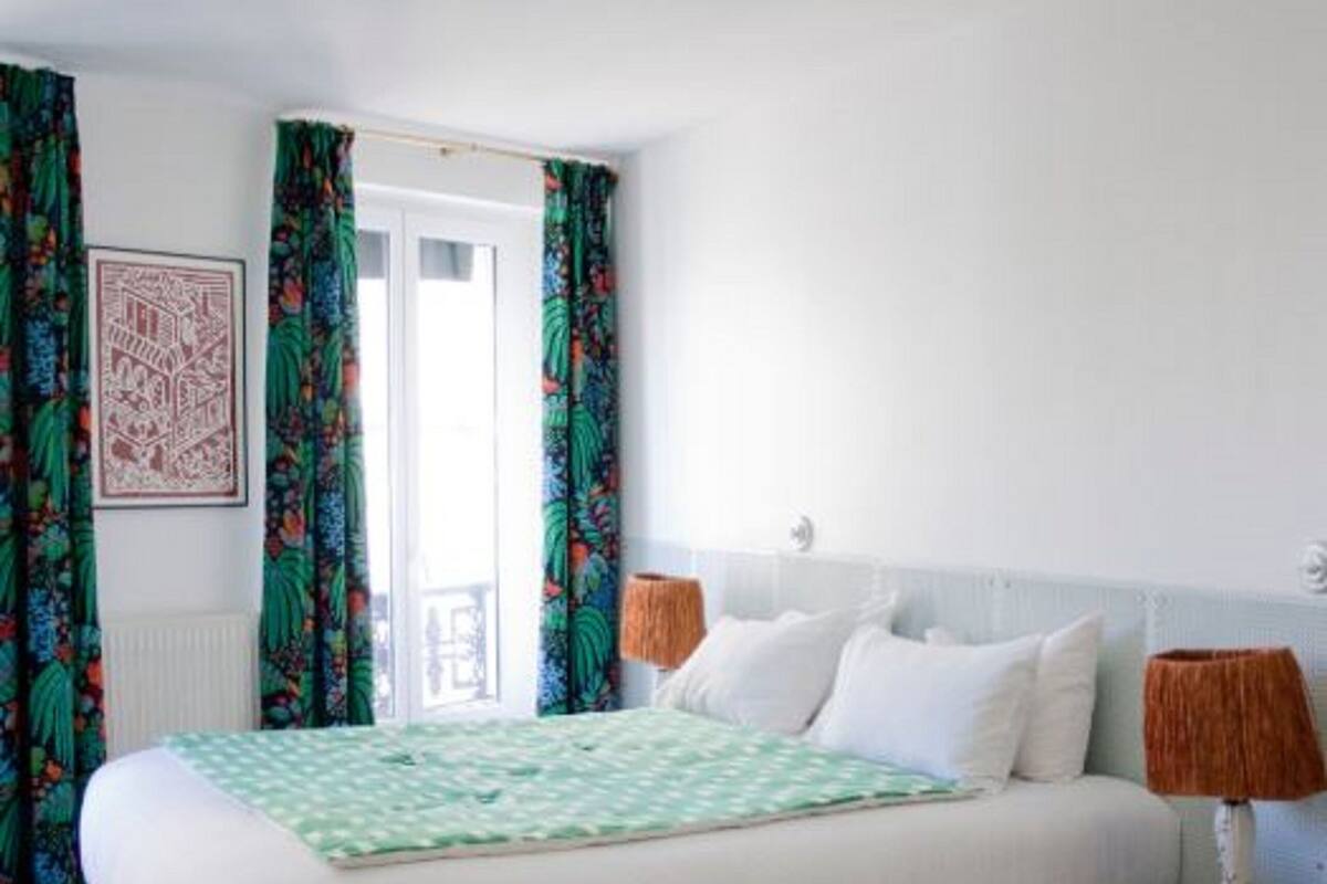 A bedroom with a bed, curtains, a nightstand, and a decorative ceiling.