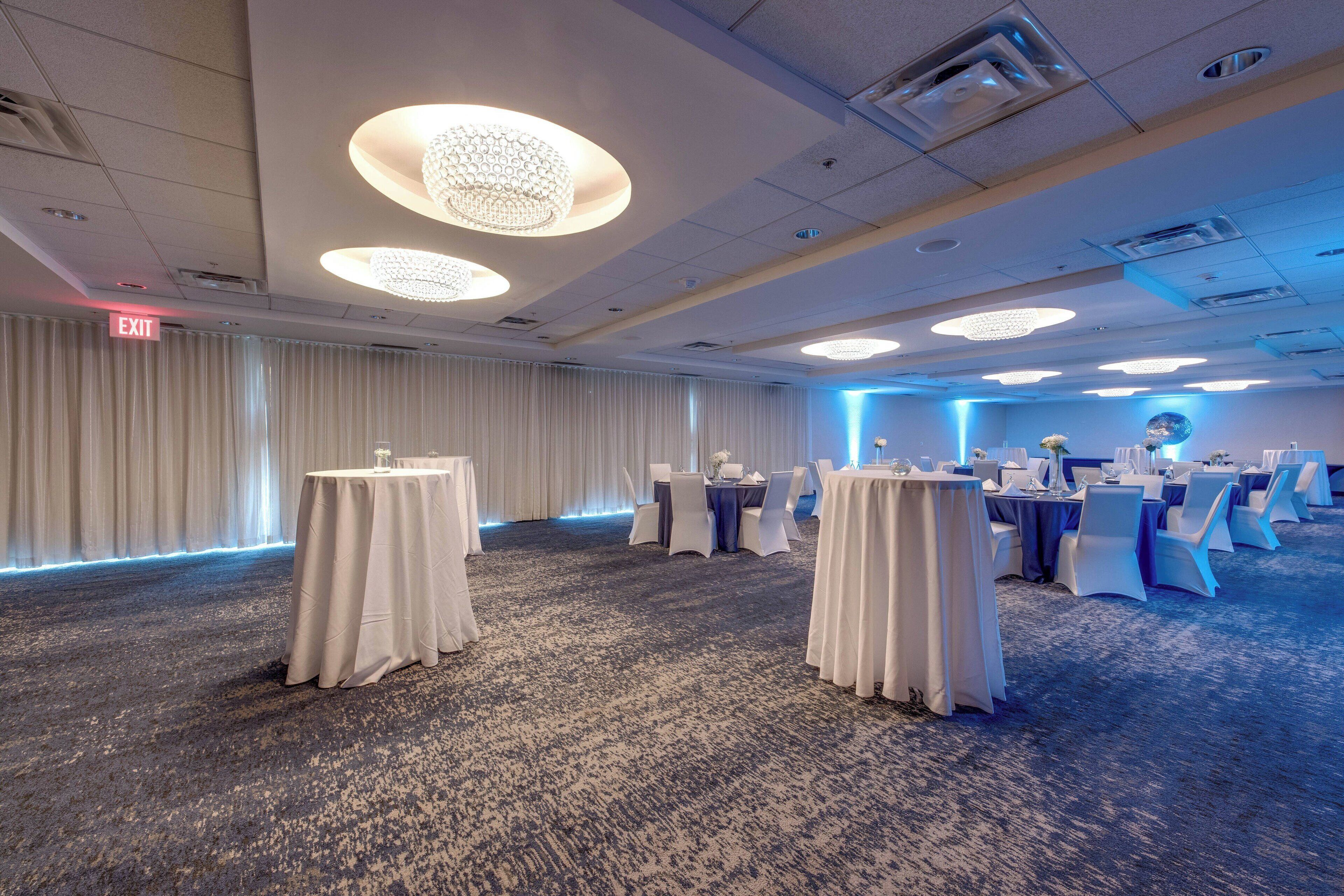 A conference room with round tables, white tablecloths, and blue chairs.