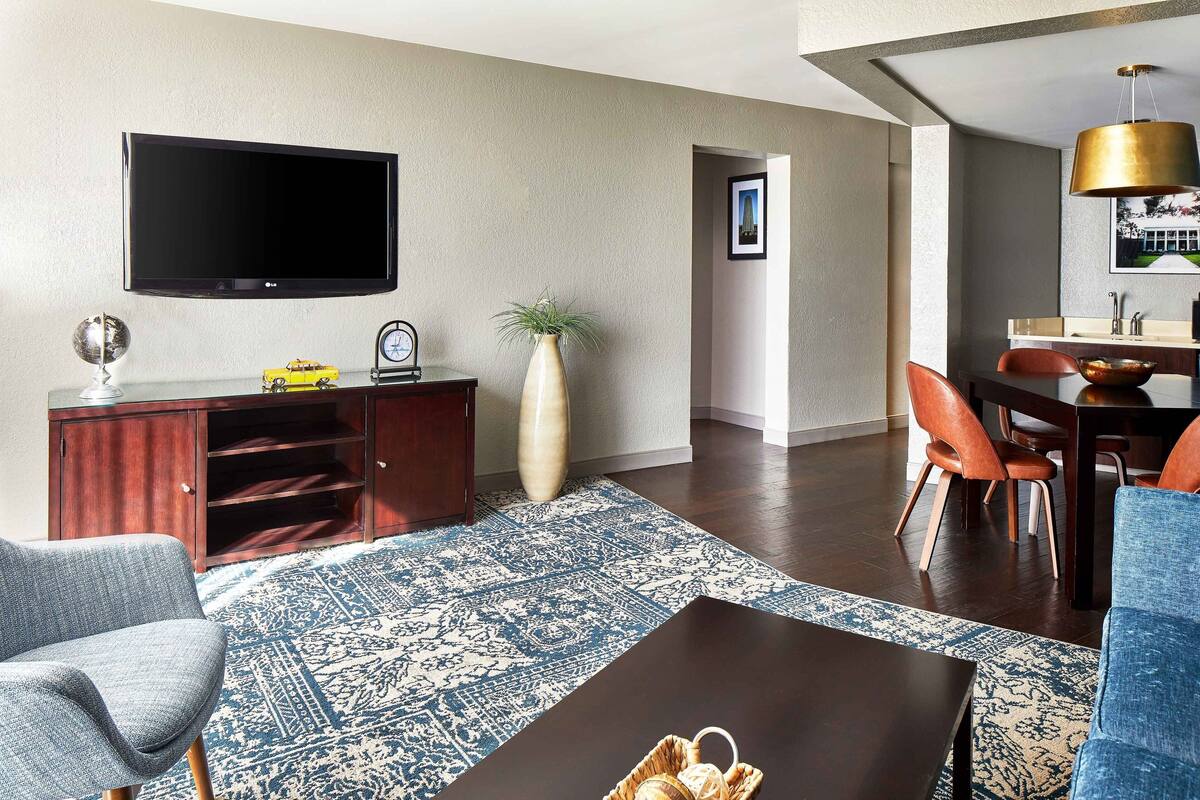 Una sala de estar moderna con un televisor de pantalla plana, una mesa de centro, un sofá y una zona de comedor con sillas y una mesa.