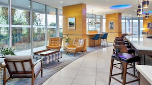 Un vestíbulo moderno con mostrador de recepción, zona de estar y ventanas amplias que ofrecen vistas al exterior.