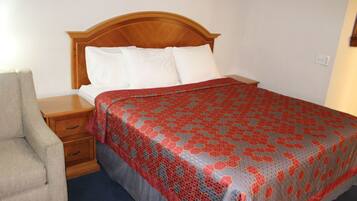 A neatly made bed with a patterned bedspread, a wooden headboard, and a bedside table with drawers.