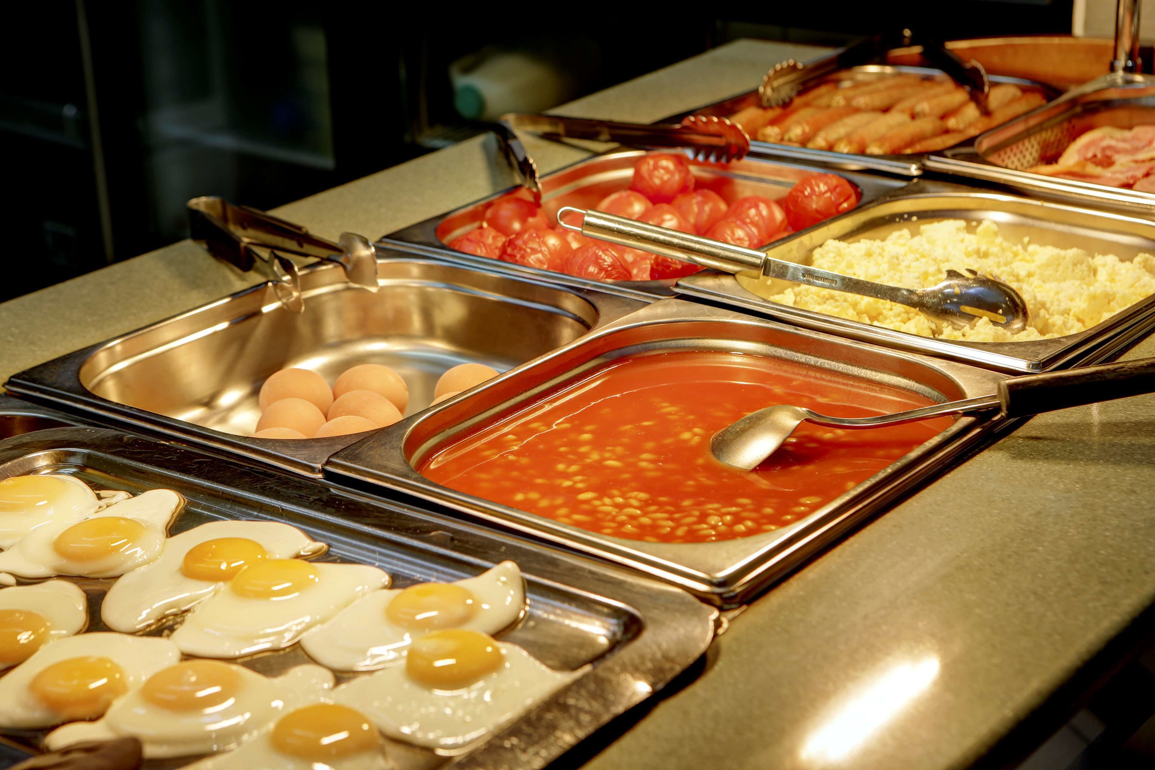 A buffet with various food options including eggs, tomatoes, and a tomato-based dish.