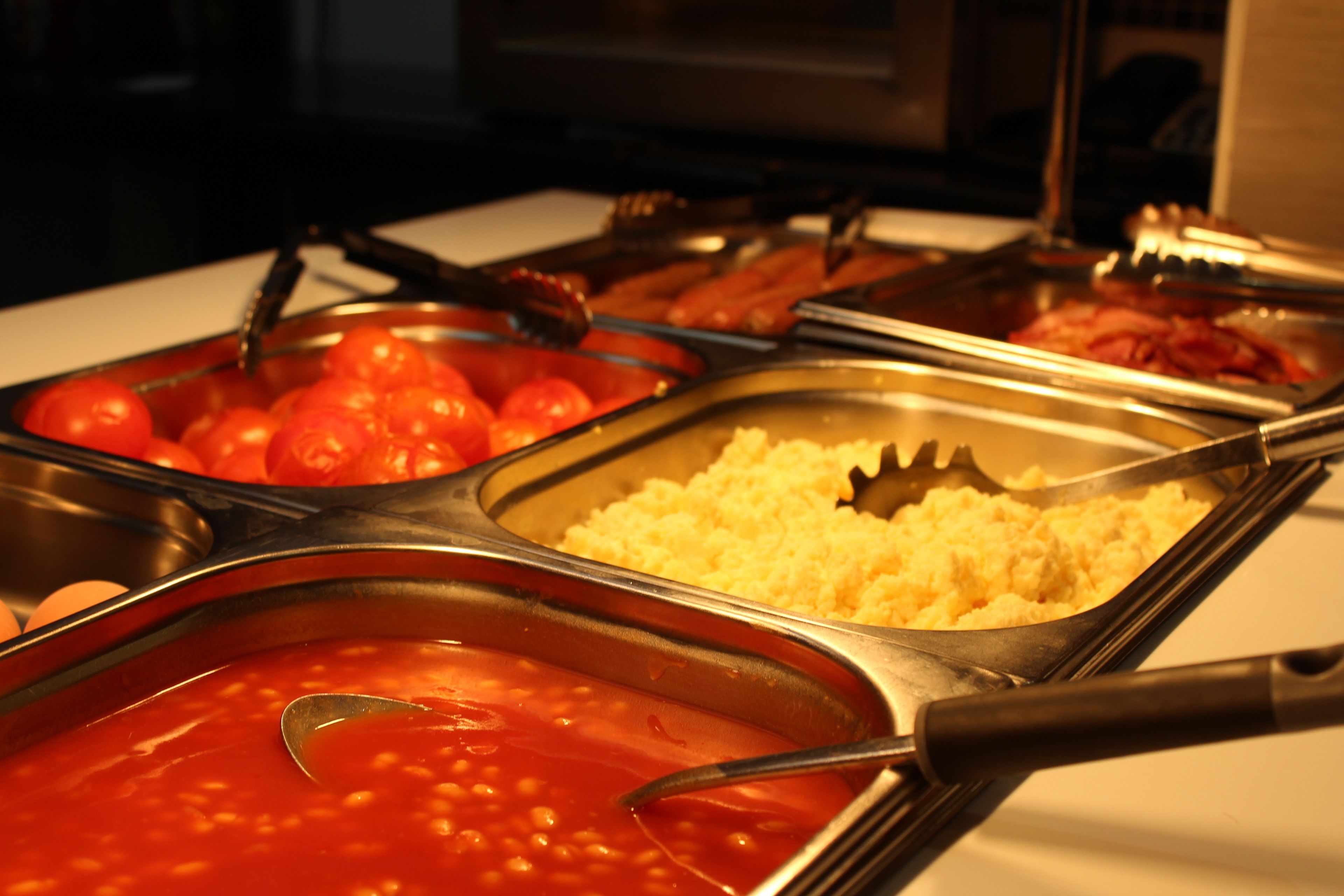 A buffet with various food items including tomatoes, rice, and beans.