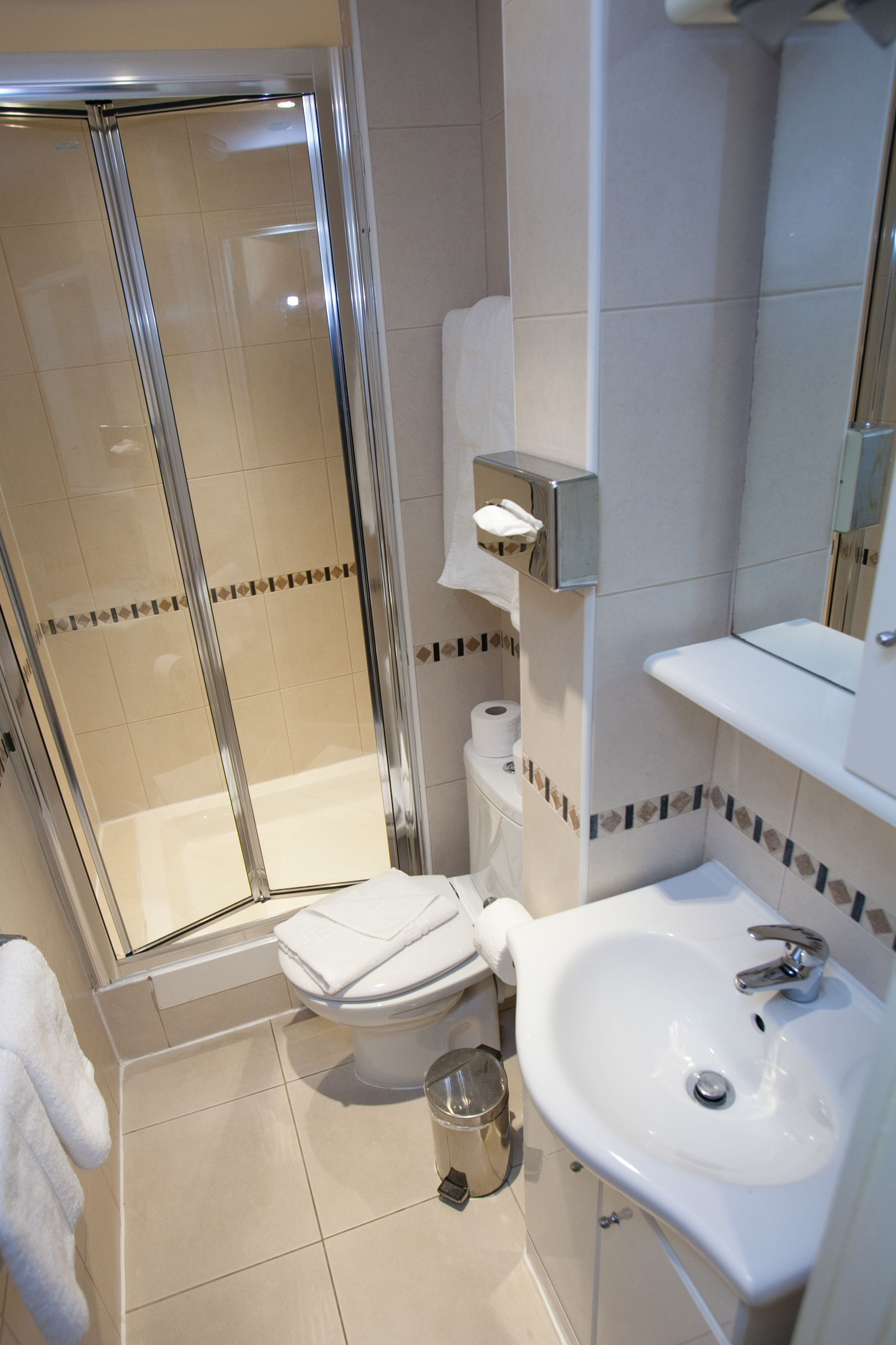 A bathroom with a shower, toilet, sink, and a mirror.