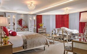 A luxurious bedroom with a large bed, two armchairs, a side table, and a mirror. - Fitzgerald's Woodlands House Hotel (Adare)