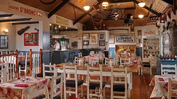 Un restaurante acogedor con mobiliario de madera, una zona de bar y diversas decoraciones, incluyendo una bicicleta y faroles.