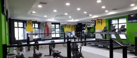 Un gimnasio con cintas de correr, máquinas de pesas y un espejo grande.