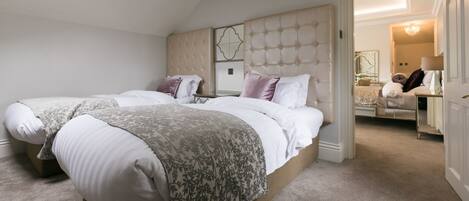A bedroom with two beds, a large window, and a chandelier.