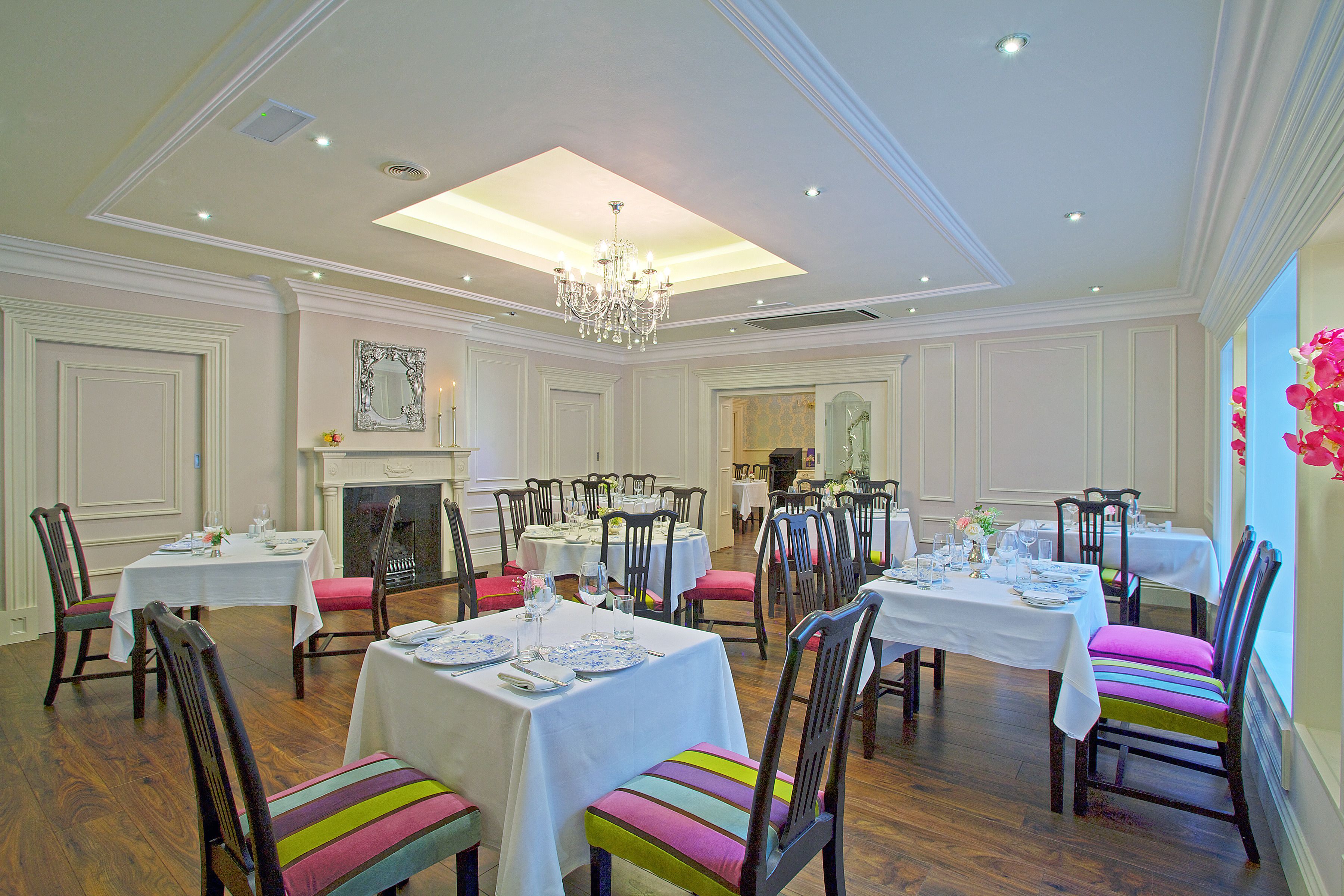 A dining area with multiple tables, chairs, and a chandelier.