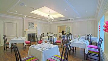 A dining area with multiple tables, chairs, and a chandelier.