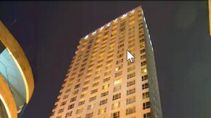 A high-rise hotel with multiple floors, large windows, and a well-lit entrance.