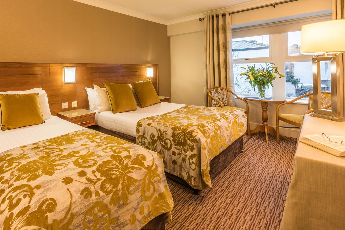 A hotel room with two beds, a desk, and a chair.