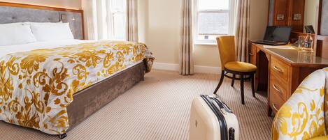 Una habitación de hotel con una cama, un escritorio, una silla y una maleta.
