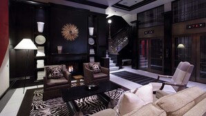 A modern living room with a fireplace, two armchairs, a sofa, a zebra-patterned rug, and a staircase leading to an upper floor. - XV Beacon (Boston)