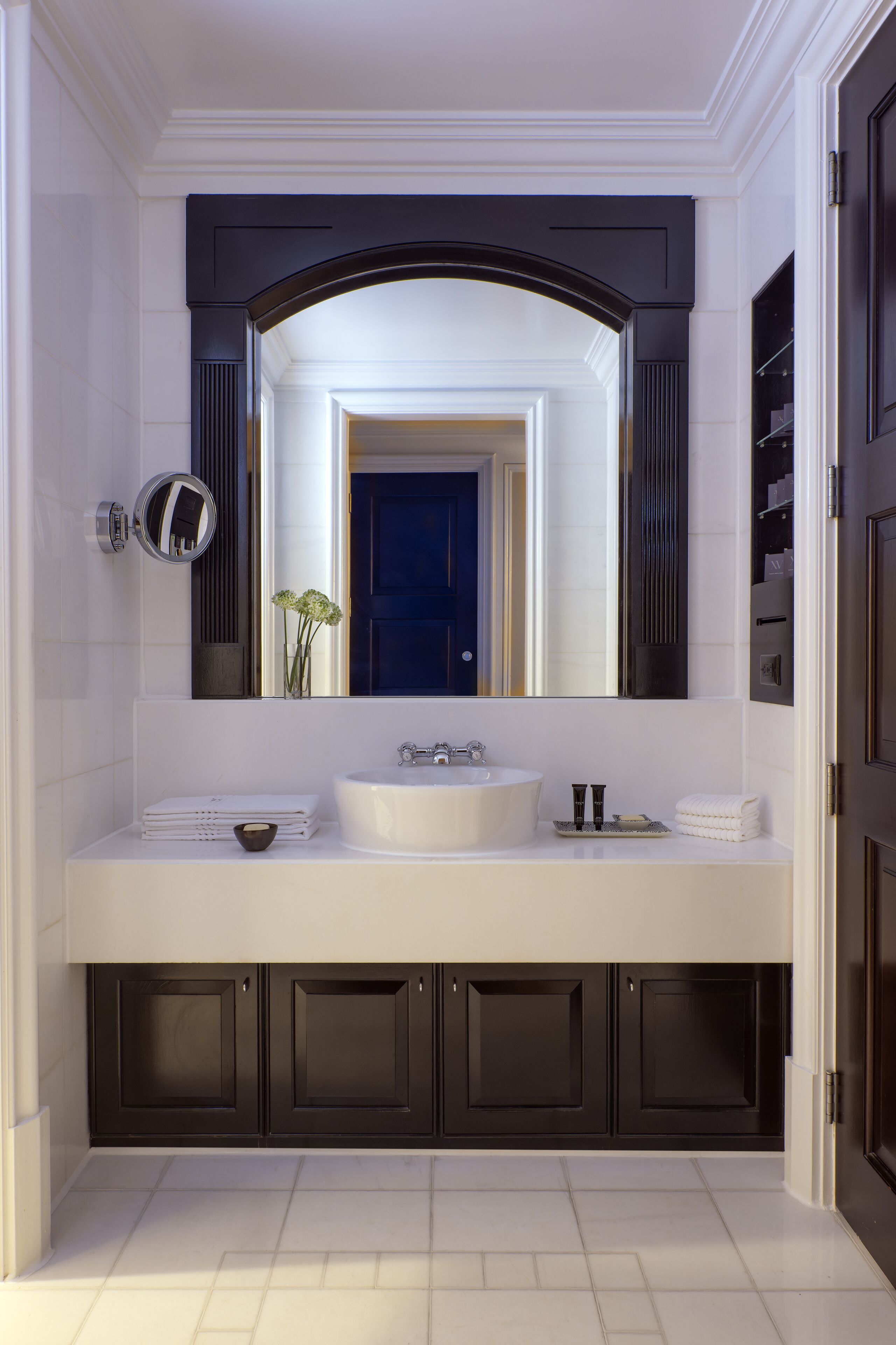 Une salle de bain moderne avec un lavabo blanc, des meubles sombres et un grand miroir au-dessus du lavabo.