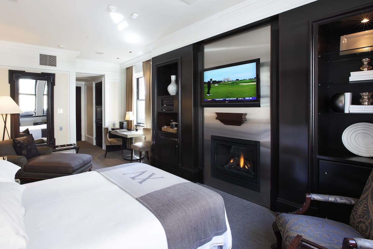 Una habitación de hotel con cama, televisión, chimenea, escritorio y una silla.