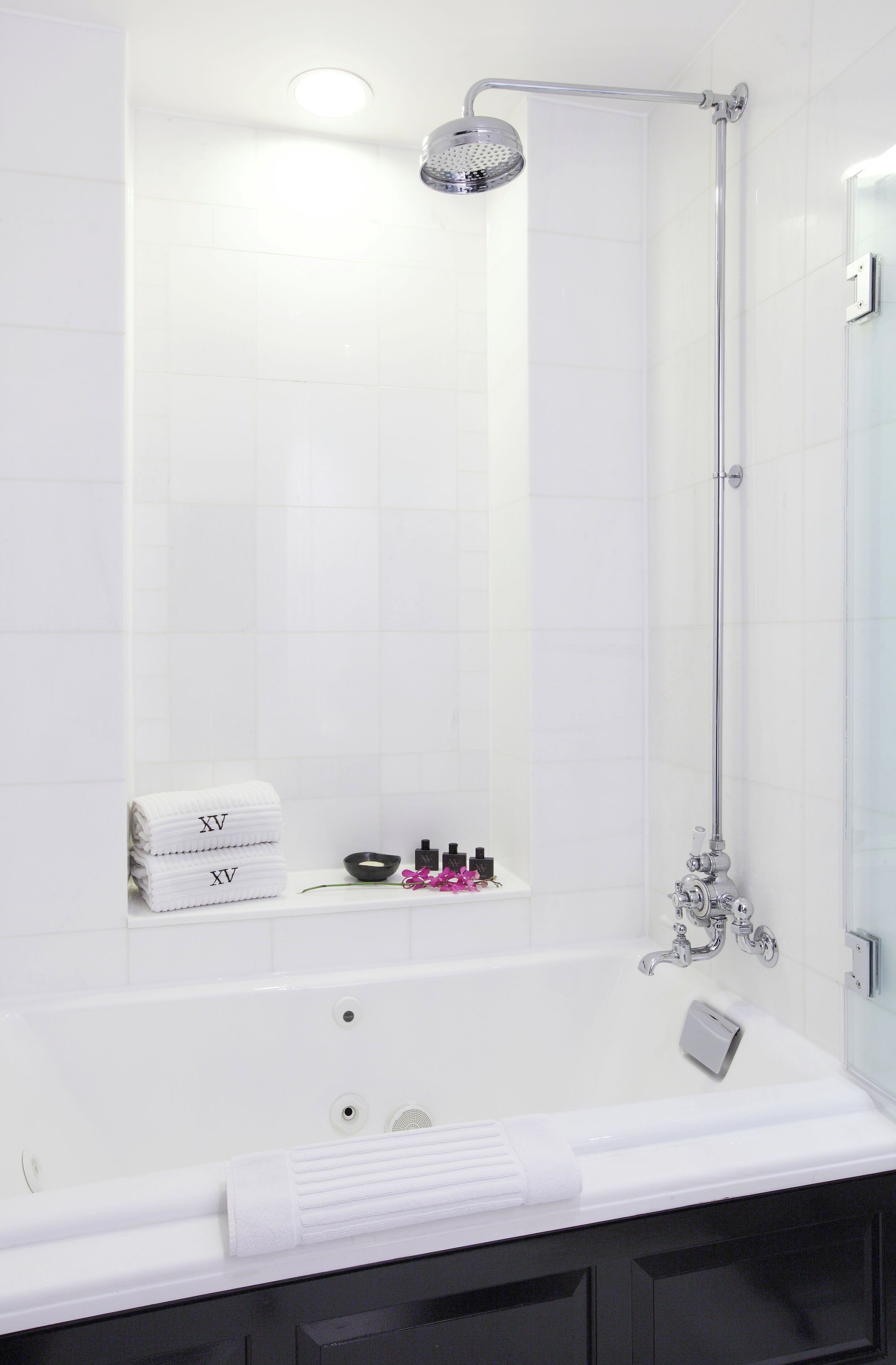 Een moderne badkamer met een bad, een douchekop en een plank met toiletartikelen.