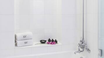 A modern bathroom with a bathtub, a showerhead, and a shelf with toiletries.