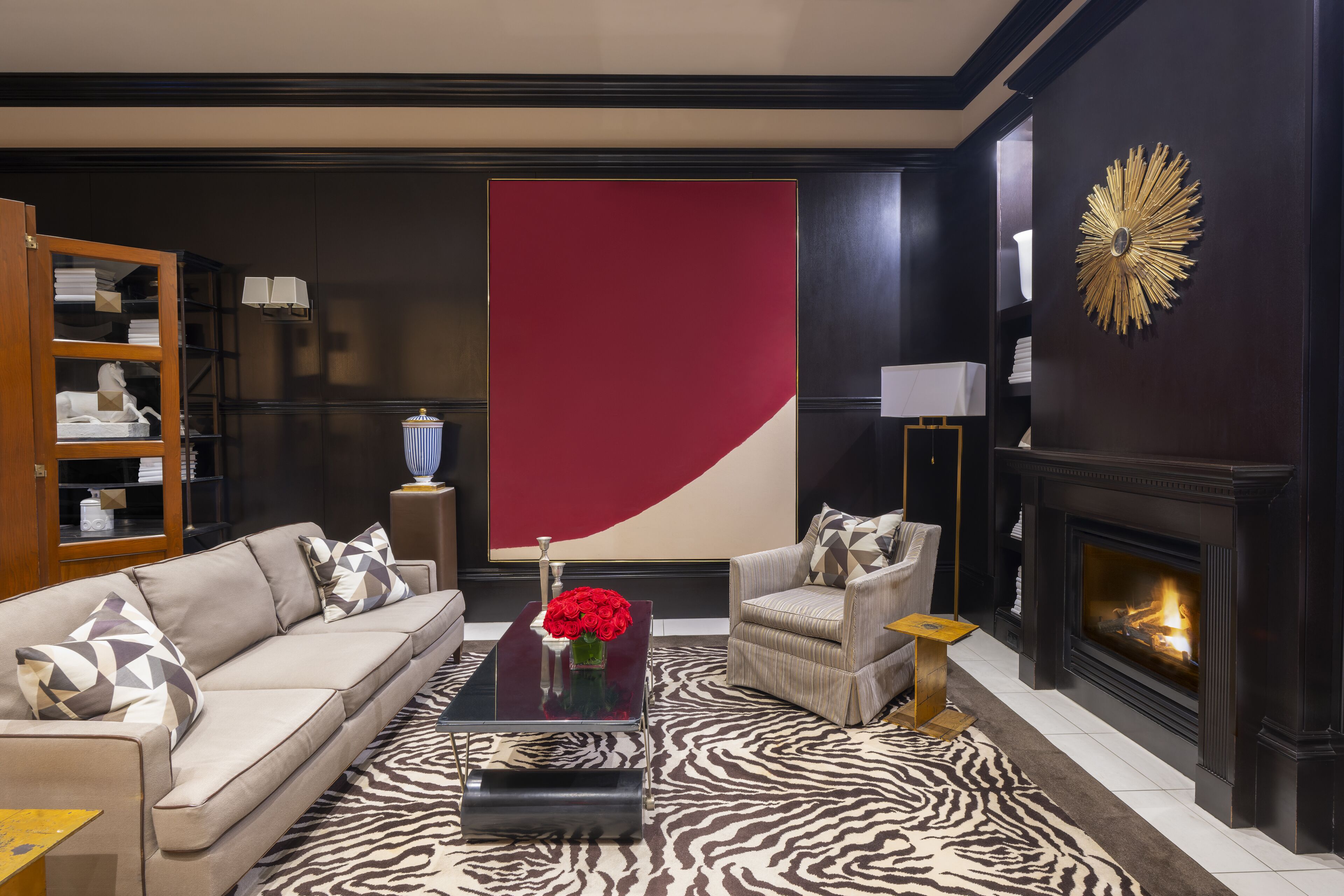 Un salon moderne comprenant un canapé, des fauteuils, une table basse, une cheminée et un grand tableau abstrait.