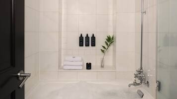 A modern bathroom with a large bathtub, a showerhead, and a small table with towels.