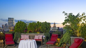A rooftop terrace with a table, chairs, and a view of the city skyline. - XV Beacon (Boston)