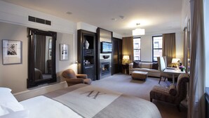 A hotel room with a large bed, a sofa, a desk, a television, and a fireplace. - XV Beacon (Boston)