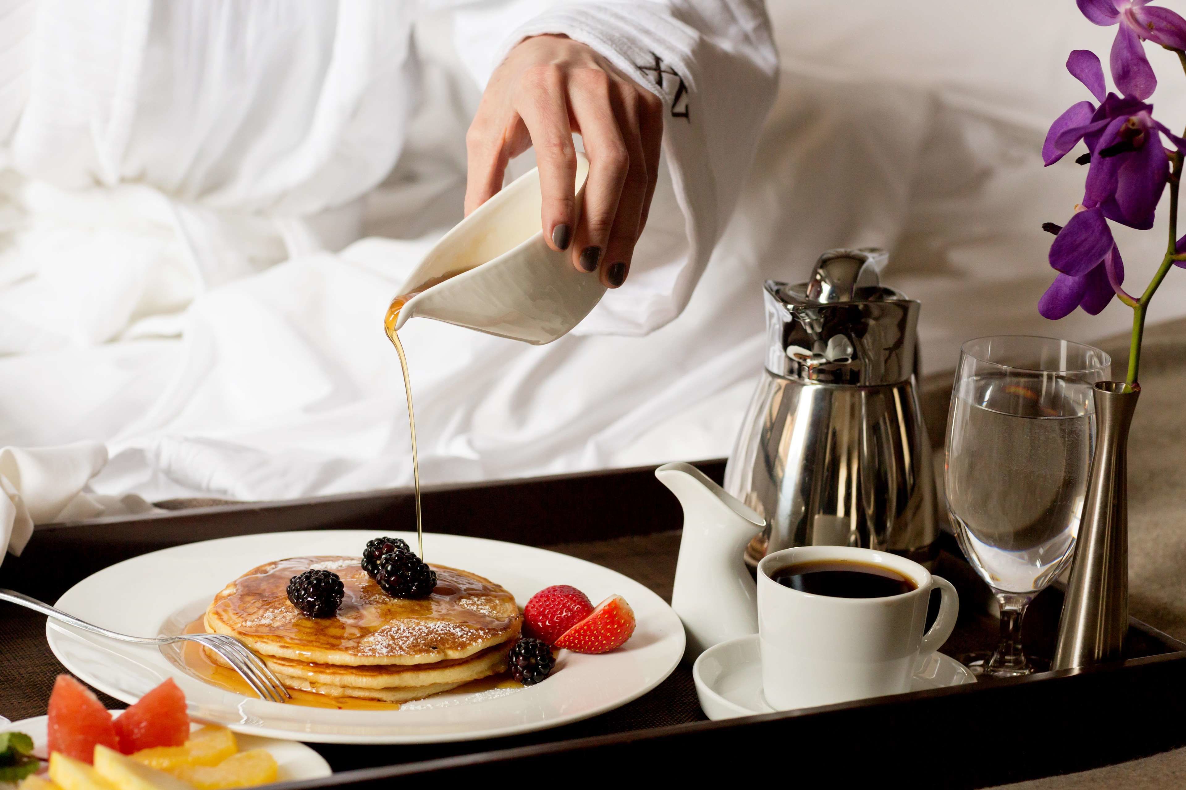 Un plateau de petit-déjeuner avec des crêpes, des fruits rouges et du café.