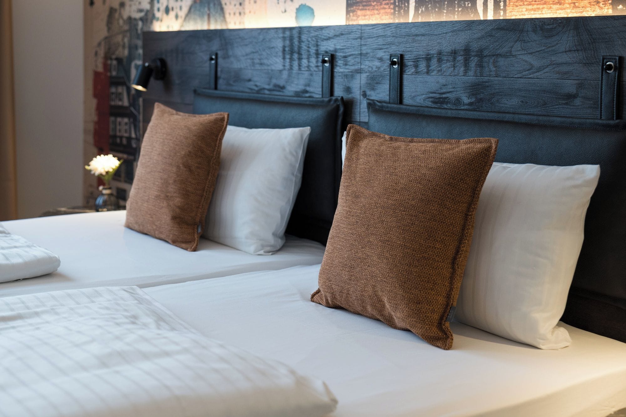 A hotel room with a bed, pillows, and a headboard.