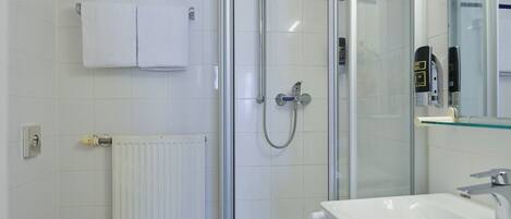A modern bathroom with a glass-enclosed shower, a white toilet, and a sink with a mirror.