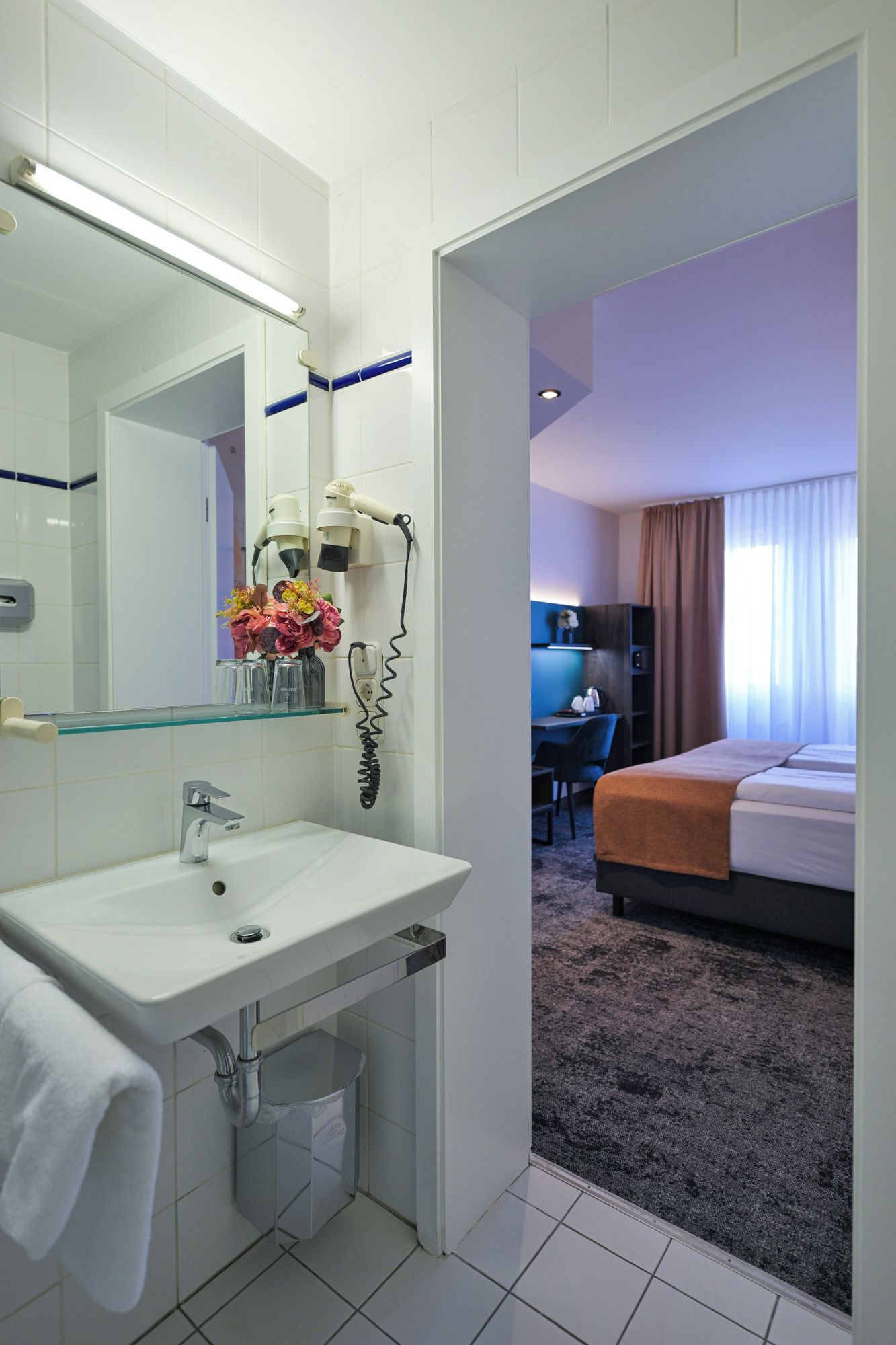 A hotel bathroom with a sink, mirror, and a telephone.