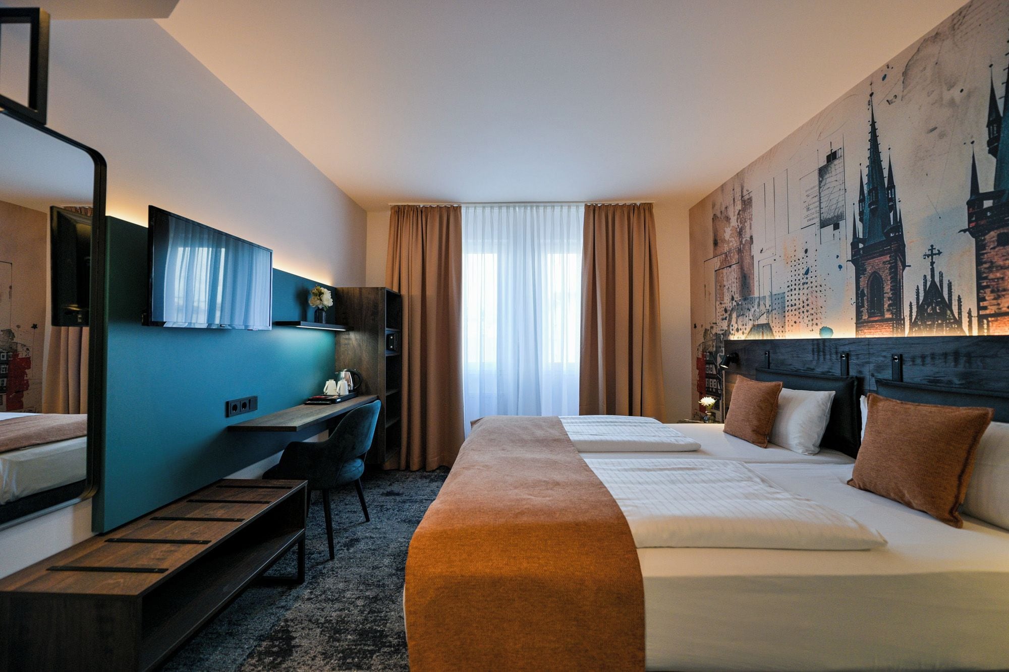 Habitación de hotel con cama, escritorio, silla, televisión y un cuadro grande con una vista urbana.