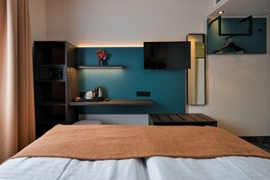A hotel room with a bed, a desk with a coffee maker, a TV, and a mirror. - Hotel Miramar Frankfurt City Centre (Frankfurt)