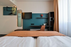 A hotel room with a bed, a desk, a chair, a TV, and a microwave. - Hotel Miramar Frankfurt City Centre (Frankfurt)