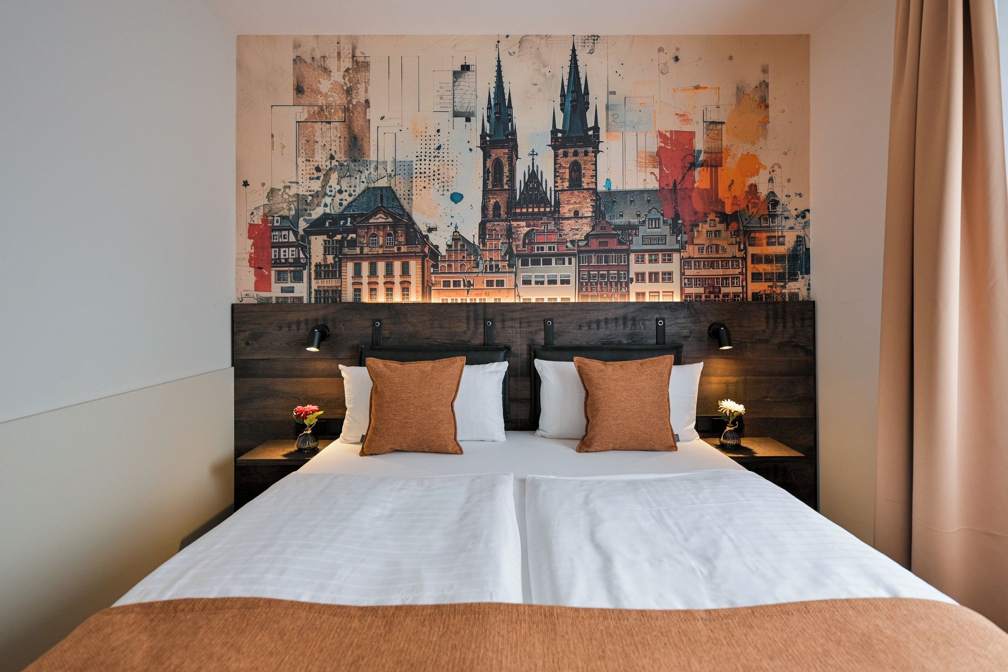 Una habitación de hotel con una cama grande, dos mesitas de noche y una obra de arte con un paisaje urbano en la pared.
