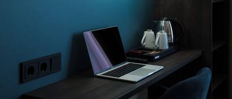 Un ordinateur portable sur un bureau, avec une machine à café et des télécommandes.
