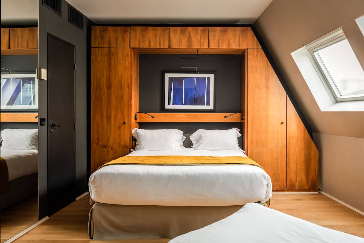 A bedroom with a bed, wooden wardrobe, and a skylight.